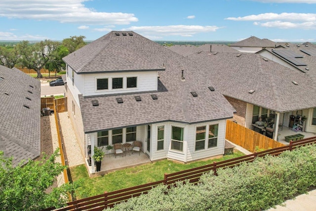 rear view of property with a patio, a shingled roof, and a fenced backyard