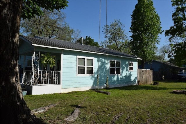 1200 NE 5th St, Smithville, TX 78957 - back of house featuring metal roof, a yard, and fence