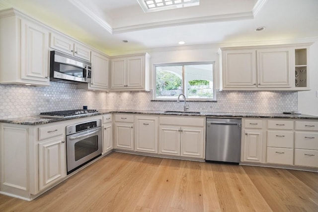 1702 Crested Butte Dr, Austin, TX 78746 - kitchen featuring appliances with stainless steel finishes, a raised ceiling, light wood finished floors, dark stone counters, and tasteful backsplash