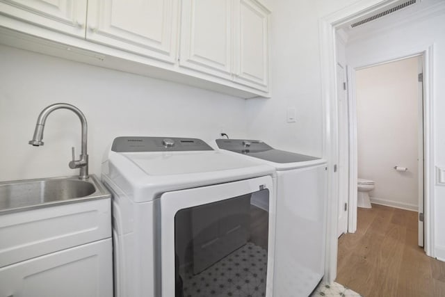 1702 Crested Butte Dr, Austin, TX 78746 - washroom with cabinet space, washer and clothes dryer, and light wood-type flooring