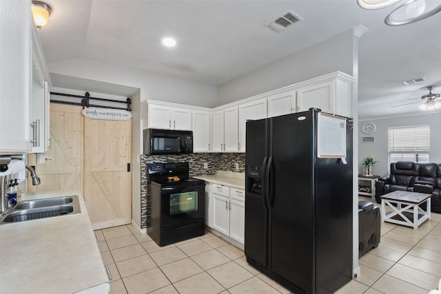 kitchen featuring black appliances, a barn door, visible vents, and a sink