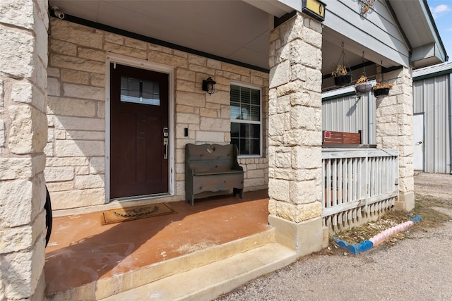 doorway to property featuring covered porch and stone siding