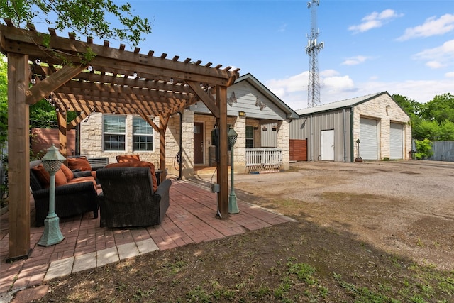 view of patio / terrace with a detached garage, a pergola, an outdoor living space, and an outbuilding