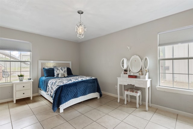 bedroom featuring baseboards, light tile patterned floors, and an inviting chandelier