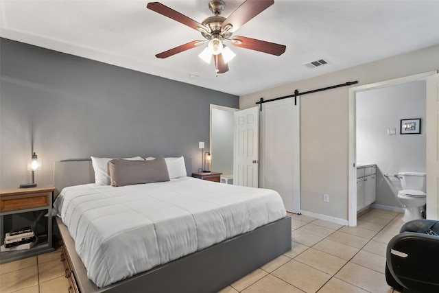 bedroom with a barn door, ensuite bathroom, baseboards, visible vents, and light tile patterned flooring