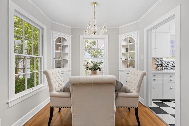 dining area with crown molding, wood finished floors, a chandelier, and baseboards