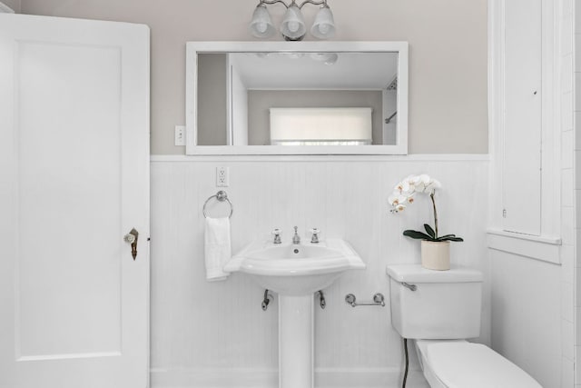 bathroom with a wainscoted wall, toilet, and a sink