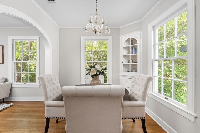 dining area with crown molding, a chandelier, arched walkways, baseboards, and wood finished floors