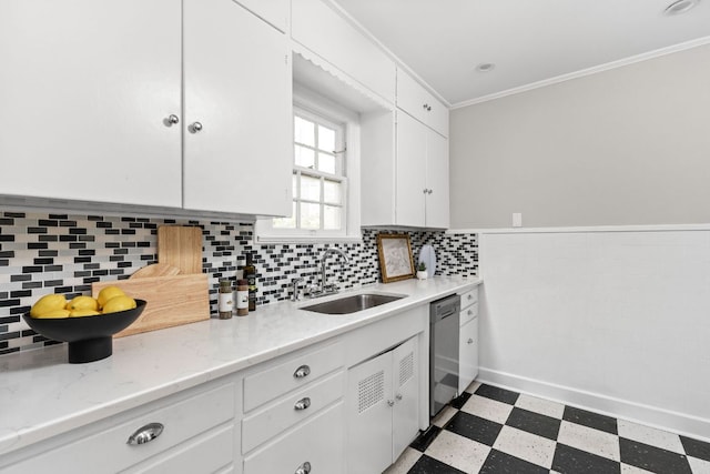 kitchen featuring a sink, tile patterned floors, crown molding, white cabinetry, and stainless steel dishwasher