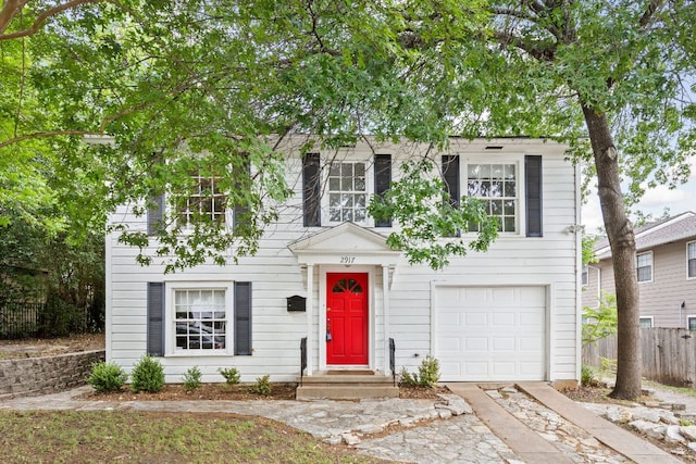 colonial inspired home with driveway, an attached garage, and fence