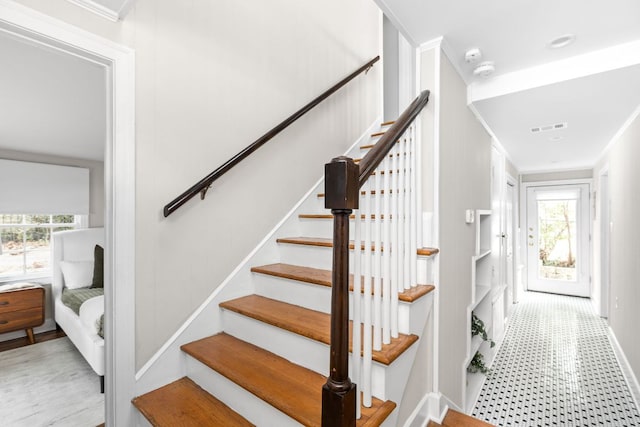 stairs with ornamental molding, visible vents, and tile patterned floors