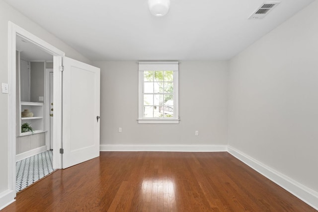 unfurnished bedroom with wood finished floors, visible vents, and baseboards