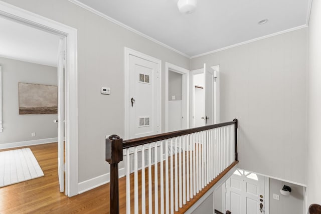 corridor featuring ornamental molding, an upstairs landing, visible vents, and light wood-type flooring