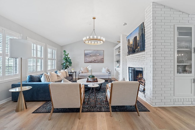 129 The Hills Dr, The Hills, TX 78738 - living room with vaulted ceiling, a chandelier, light wood-style floors, and a brick fireplace