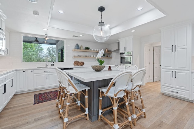129 The Hills Dr, The Hills, TX 78738 - kitchen featuring oven, a tray ceiling, open shelves, a breakfast bar, and white cabinetry