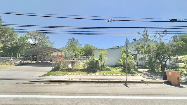 view of front facade with concrete driveway, a carport, and fence