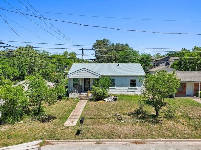 view of front of house with a porch, a front lawn, and metal roof