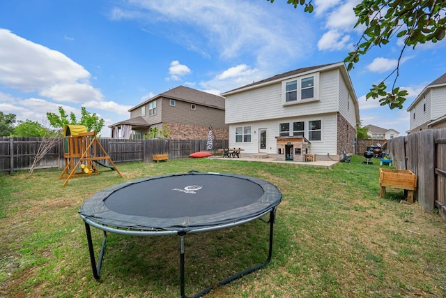 back of property featuring a fenced backyard, a patio area, a yard, and a trampoline