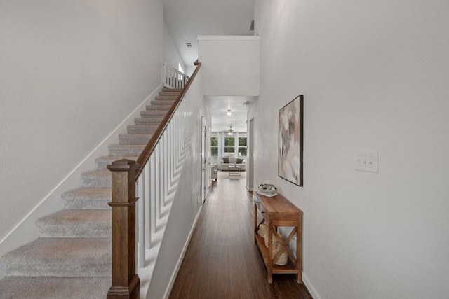 staircase with wood finished floors, ceiling fan, and a high ceiling