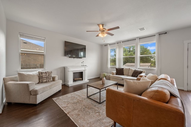 living room with a wealth of natural light, visible vents, a ceiling fan, and a fireplace