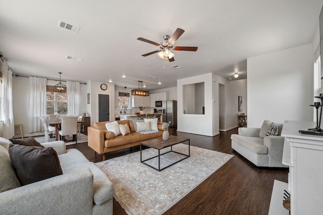 living area featuring dark wood-style floors, visible vents, ceiling fan, and baseboards