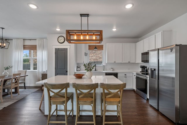 kitchen featuring white cabinets, light countertops, dark wood-style floors, a center island, and black appliances