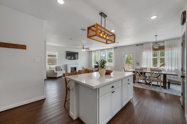 kitchen with white cabinetry, light countertops, a center island, recessed lighting, and a fireplace