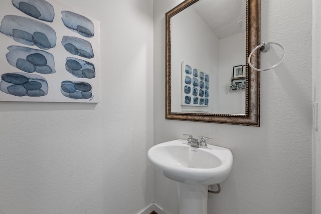 bathroom featuring baseboards and a sink