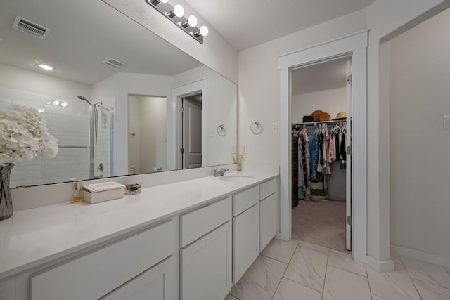 bathroom with vanity, a tile shower, marble finish floor, visible vents, and a spacious closet