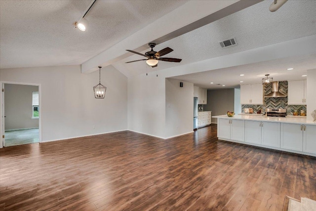 unfurnished living room featuring lofted ceiling with beams, ceiling fan, visible vents, a textured ceiling, and dark wood finished floors