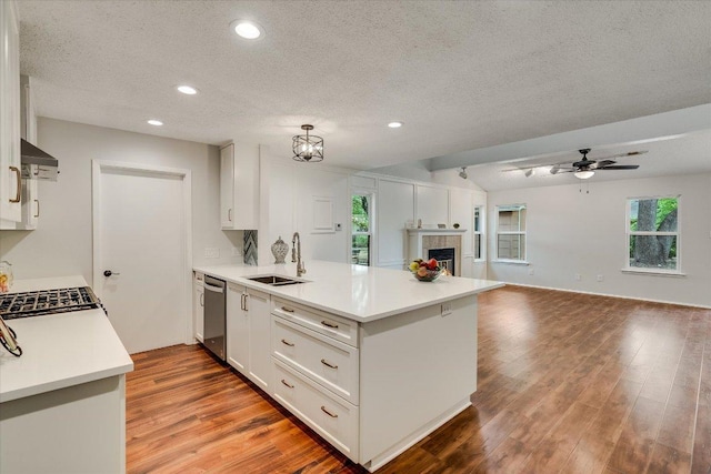kitchen featuring a sink, a peninsula, stainless steel dishwasher, a textured ceiling, and open floor plan