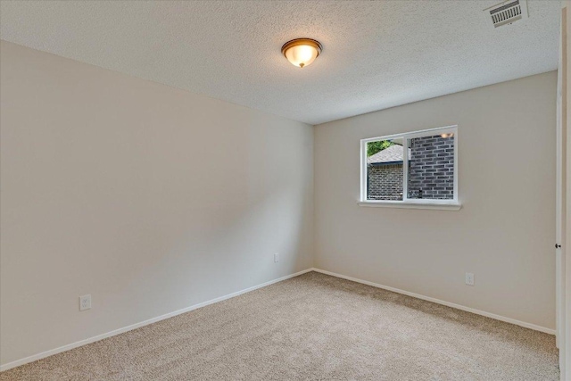 carpeted empty room with baseboards, visible vents, and a textured ceiling
