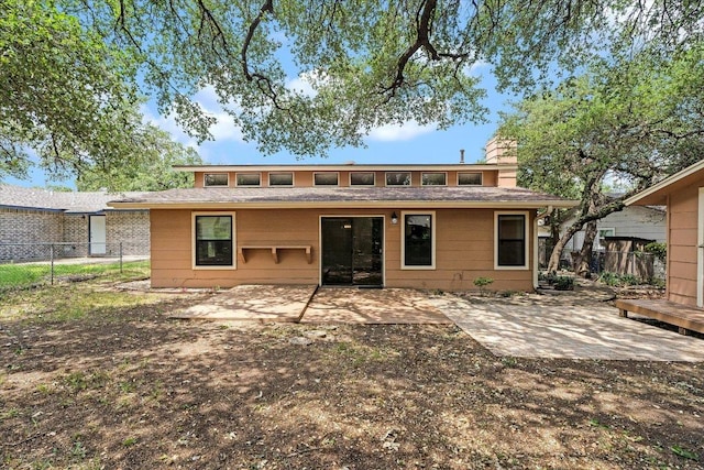 back of property with fence, a chimney, and a patio