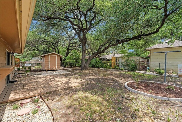 view of yard featuring fence, an outdoor structure, a wooden deck, and a storage shed