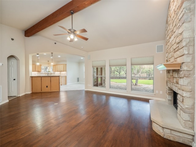 2912 Norton Ave, Lago Vista, TX 78645 - unfurnished living room with a ceiling fan, a stone fireplace, dark wood-type flooring, and arched walkways