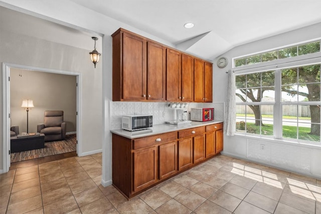 30310 Bumble Bee Dr, Georgetown, TX 78628 - kitchen featuring brown cabinetry, light countertops, vaulted ceiling, and tasteful backsplash
