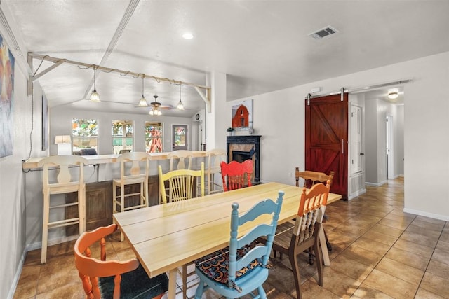30310 Bumble Bee Dr, Georgetown, TX 78628 - dining space with a barn door, a fireplace, a ceiling fan, baseboards, and visible vents