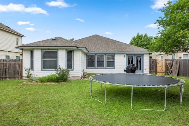 107 Jefferson Cv, Elgin, TX 78621 - rear view of property with a trampoline, a fenced backyard, and a yard