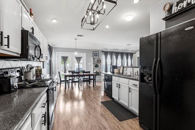 107 Jefferson Cv, Elgin, TX 78621 - kitchen featuring recessed lighting, wood finished floors, black appliances, a sink, and visible vents