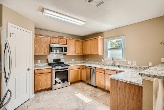 8201 Georgie Trace Ave, Austin, TX 78747 - kitchen featuring appliances with stainless steel finishes, a peninsula, and a textured ceiling