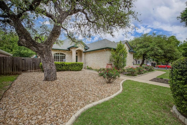 ranch-style house with fence, a front lawn, and stone siding