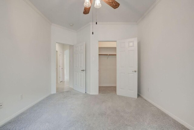 unfurnished bedroom featuring crown molding, carpet flooring, a closet, baseboards, and a walk in closet