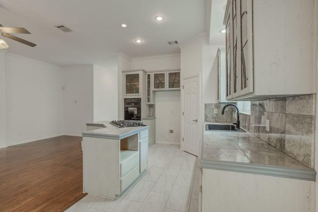 kitchen with crown molding, black oven, a sink, visible vents, and a ceiling fan