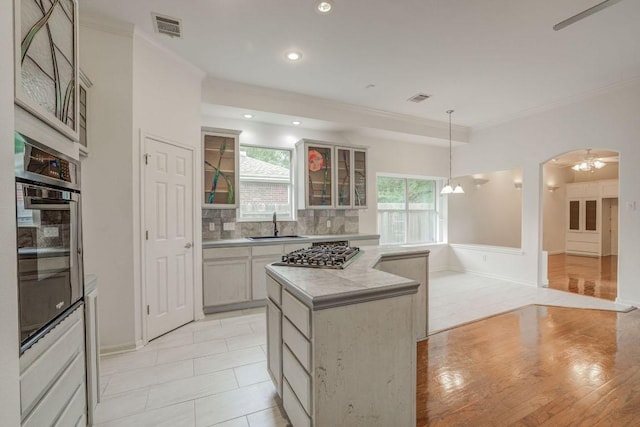 kitchen featuring crown molding, wall oven, a sink, and stainless steel gas stovetop