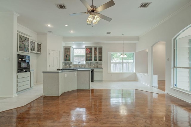 kitchen featuring glass insert cabinets, black oven, visible vents, and light wood-style floors