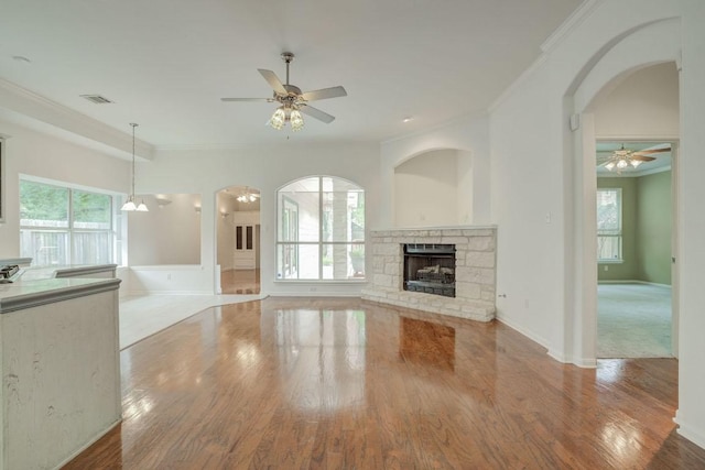 unfurnished living room with wood finished floors, ceiling fan, and crown molding