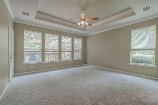 spare room with crown molding, visible vents, ceiling fan, a tray ceiling, and carpet floors