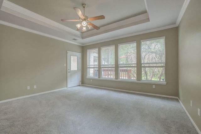 carpeted empty room featuring a wealth of natural light, ceiling fan, and a raised ceiling