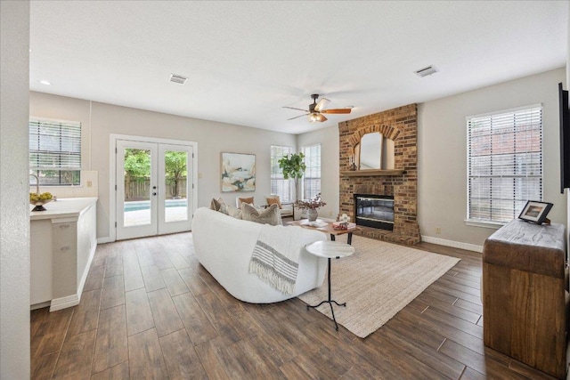 9007 Tweed Berwick Dr, Austin, TX 78750 - living room featuring ceiling fan, dark wood finished floors, a brick fireplace, french doors, and baseboards