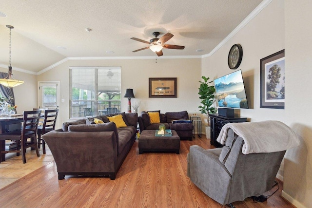 living area featuring light wood-style flooring, ceiling fan, ornamental molding, and vaulted ceiling